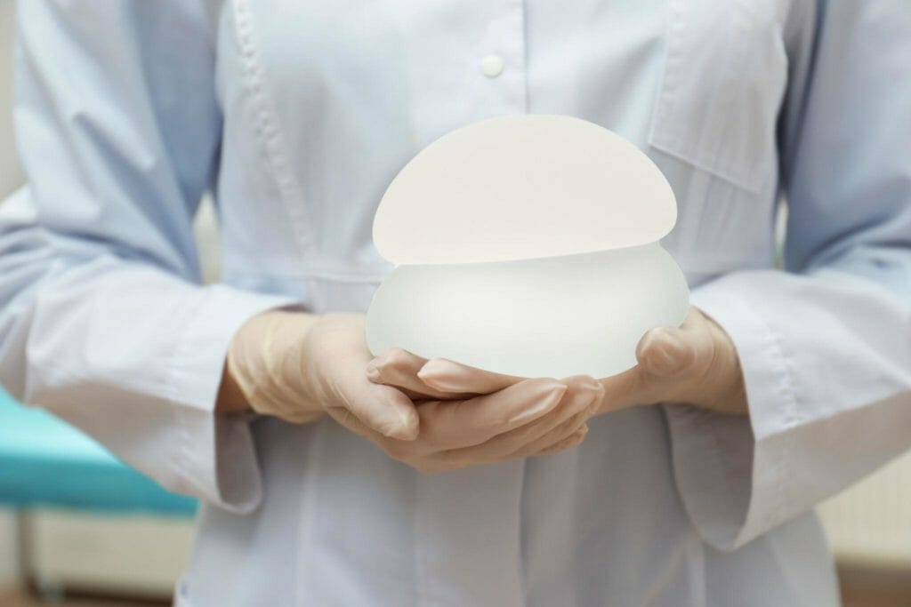 Doctor holding silicone implants for breast augmentation in clinic, closeup. Cosmetic surgery