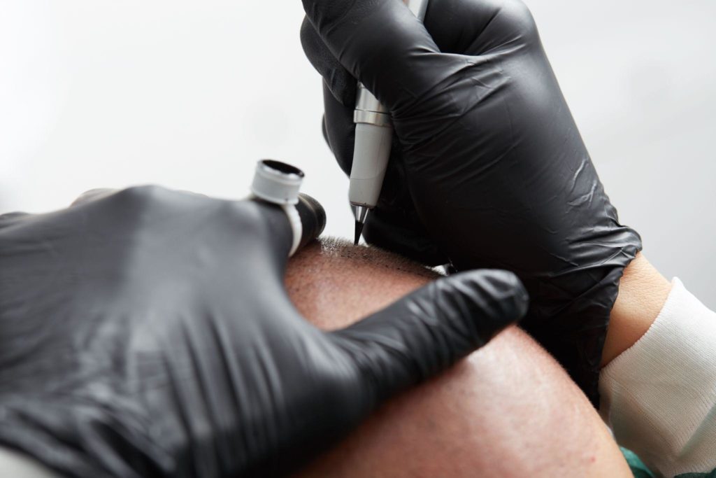 Professional tattooist making tattoo on man skin head